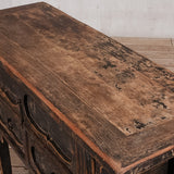 Wooden table with a rustic finish on a wooden floor.