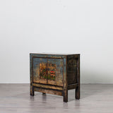 A rustic, weathered wooden cabinet with a distressed blue and orange painted front, standing on a light gray floor against a white wall.