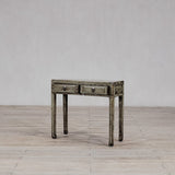 Wooden console table with two drawers on a wooden floor against a plain wall.