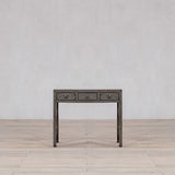 Wooden console table with three drawers against a plain wall.
