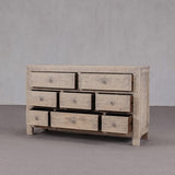 Wooden dresser with multiple drawers against a plain background