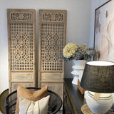 Decorative room with wooden panels, wicker chair, and table with lamp and decor items.