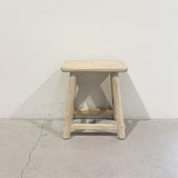 Wooden stool on a concrete floor with a white wall background