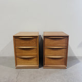 Two wooden nightstands with multiple drawers on a plain background