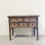 Wooden console table with wicker drawers against a white wall