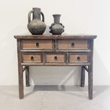 Wooden console table with wicker drawers and two rustic vases on a white background