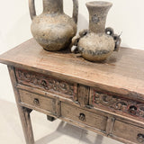 Two rustic clay pots on a wooden sideboard with intricate carvings.