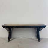 Wooden table with dark blue painted legs against a white wall