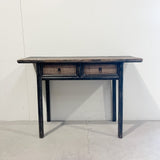 Wooden console table with two drawers against a white wall