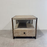 Wooden side table with a drawer against a white wall