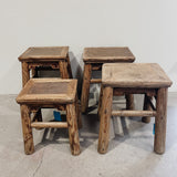 Set of four wooden stools with woven tops on a concrete floor.