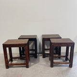 Set of four wooden stools against a plain white wall.