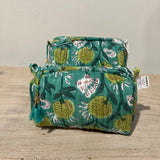 Two green fabric pouches with floral patterns on a wooden surface.