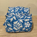 Blue and white floral patterned bags on a wooden surface with a beige background
