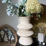 Decorative table setting with a vase of flowers and candles on a white surface.
