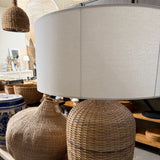 Close-up of a woven chair and a white lampshade.