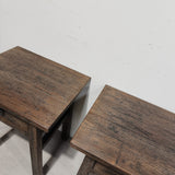 Two rustic dark brown wooden side tables shown from an elevated angle against a plain off-white wall.