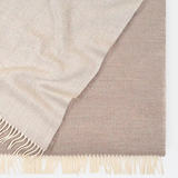 Close-up of a beige and brown woven blanket with fringes on a white background