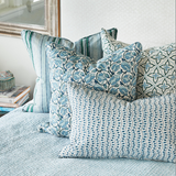 Patterned pillows on a bed with a mirror in the background
