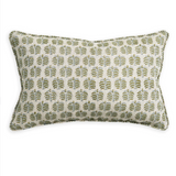 A rectangular lumbar throw pillow featuring an all-over repeating block-printed leaf pattern in muted green and blue on a warm cream linen-like fabric, finished with a matching green piped edge.