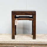 Antique rectangular top stool made of reclaimed wood, with visible variations in color, placed on a textured surface.