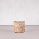 Woven cylindrical container on a light gray surface with a white background