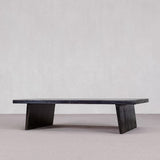Long, dark wooden bench against a plain light gray wall.