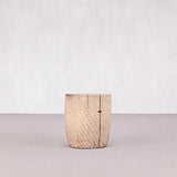Wooden cylindrical object on a light gray surface with a white background