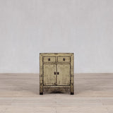 Vintage wooden cabinet with chipped paint on a wooden floor and light gray wall background