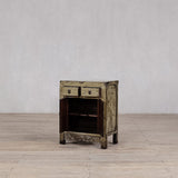 Vintage wooden side table with two drawers on a wooden floor against a gray wall.