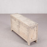Wooden sideboard with a distressed white finish on a plain background