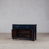 Vintage wooden cabinet with open door on a wooden floor against a gray wall