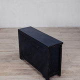 Black wooden sideboard on a wooden floor with a white wall background