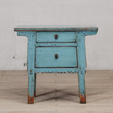 Vintage blue wooden side table with a single drawer on a wooden floor.