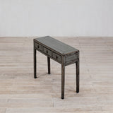 Wooden console table with three drawers on a wooden floor.