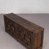 Wooden bench with geometric patterns on a gray floor and white wall background