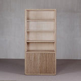 Wooden bookshelf with a textured finish against a gray wall.