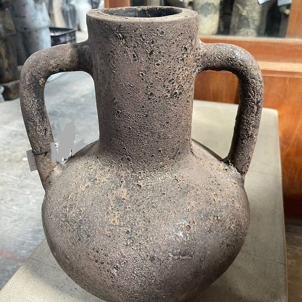 Brown ceramic vase with handles on a concrete surface