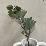 Artificial plant in a white vase against a plain wall