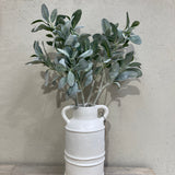 White wall-mounted planter with a plant against a neutral background