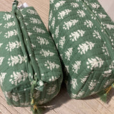 Green quilted bags with white tree pattern on a wooden surface