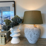 Decorative lamp with a textured base and green shade on a wooden surface.