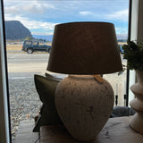 Two flower pots on a windowsill with a scenic view outside.