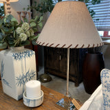 Decorative lamp with beige shade on a wooden table with plants and candle