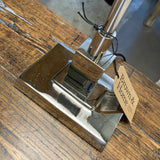 Metallic object with a tag labeled 'Brown & Home' on a wooden surface