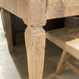 Close-up of a wooden chair with visible wear and tear on a concrete floor.
