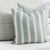 Patterned pillows on a bed with a textured wall background