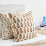Decorative pillows with floral and leaf patterns on a bed.