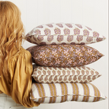 Stack of patterned pillows with a person wearing a mustard yellow shirt.