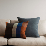 Two decorative pillows on a beige sofa against a plain wall.